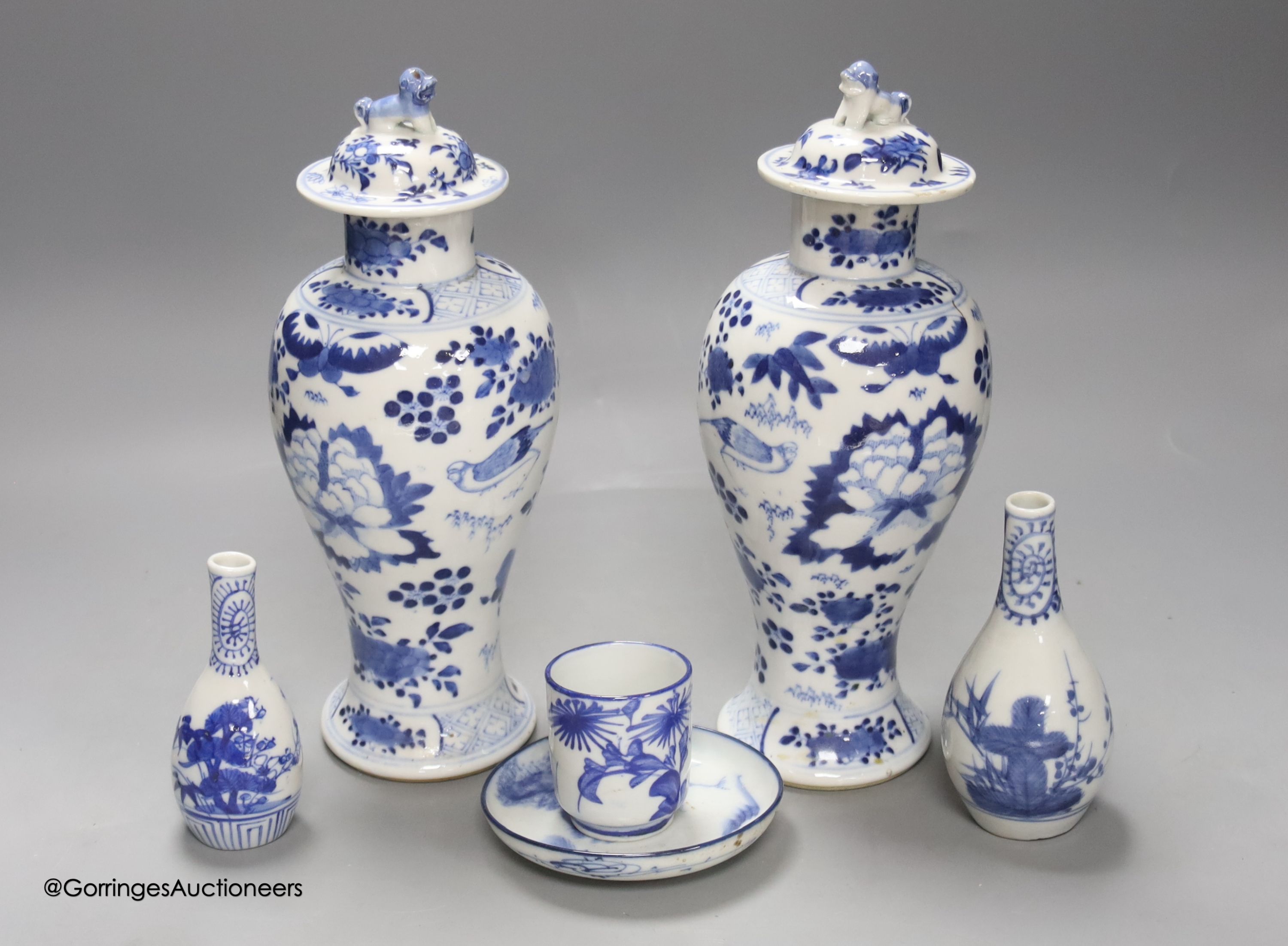 A pair of lidded Chinese blue and white vases, c.1900, Kangxi marks, 23cm high, together with two small Japanese vases, and a cup and saucer (6)